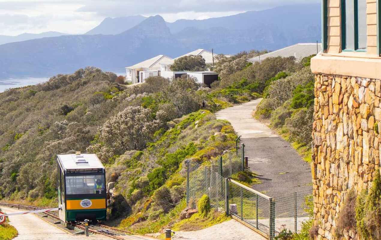 Vibrant green and yellow Flying Dutchman Funicular car pulling into the top station on Cape Point