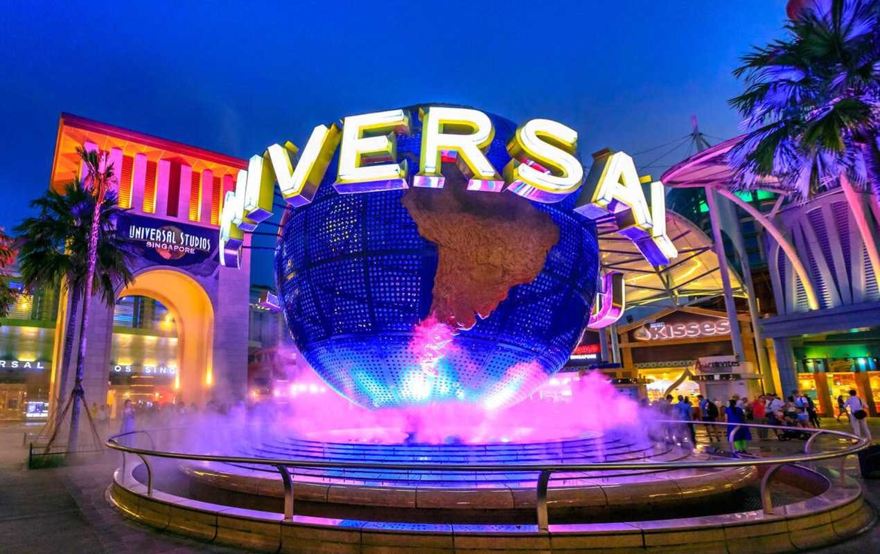 The luminous globe of Universal Studios in Sentosa Island at blue hour with pink lights.