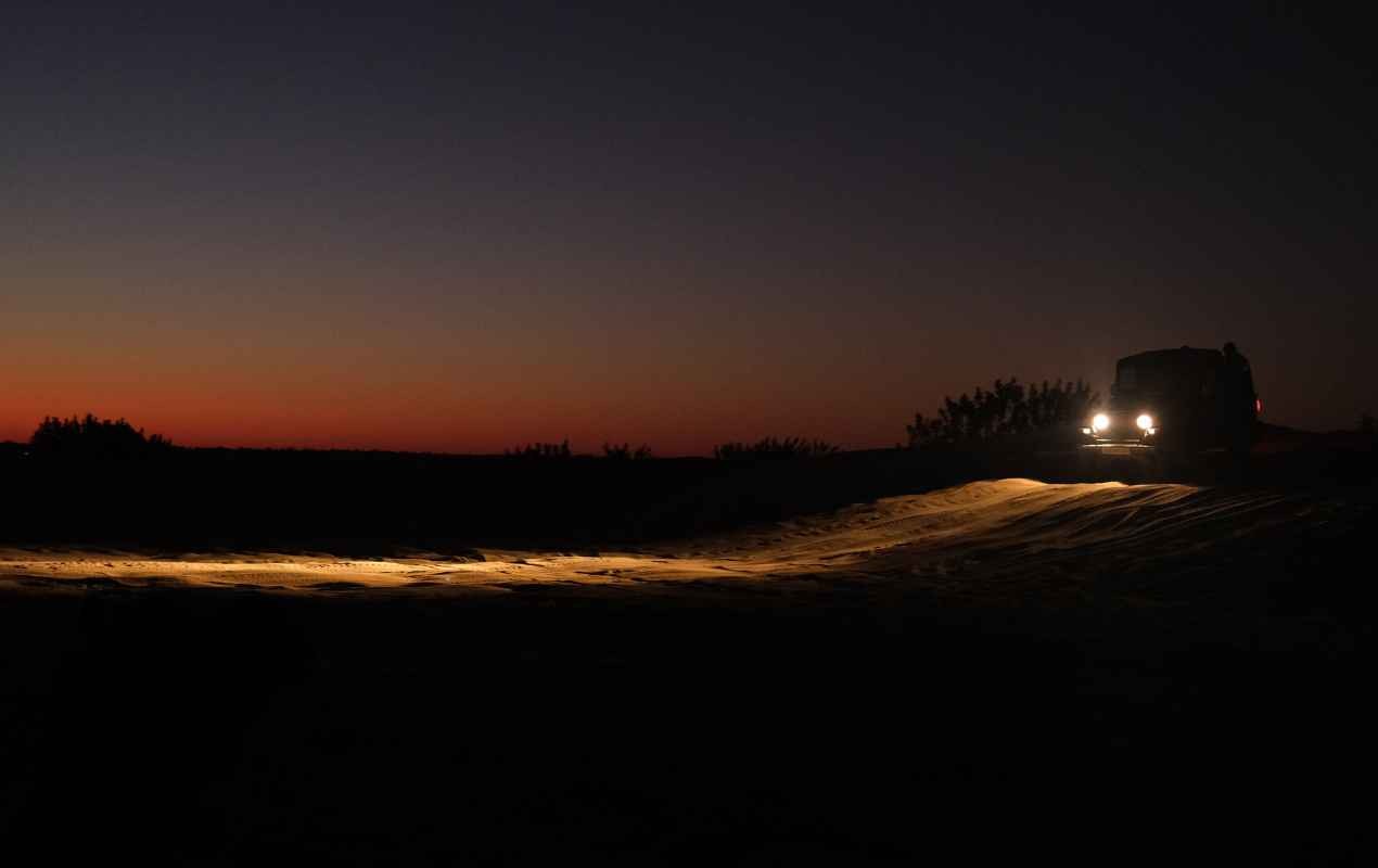 The stunning hues of the setting sun as a jeep zooms through the desert.